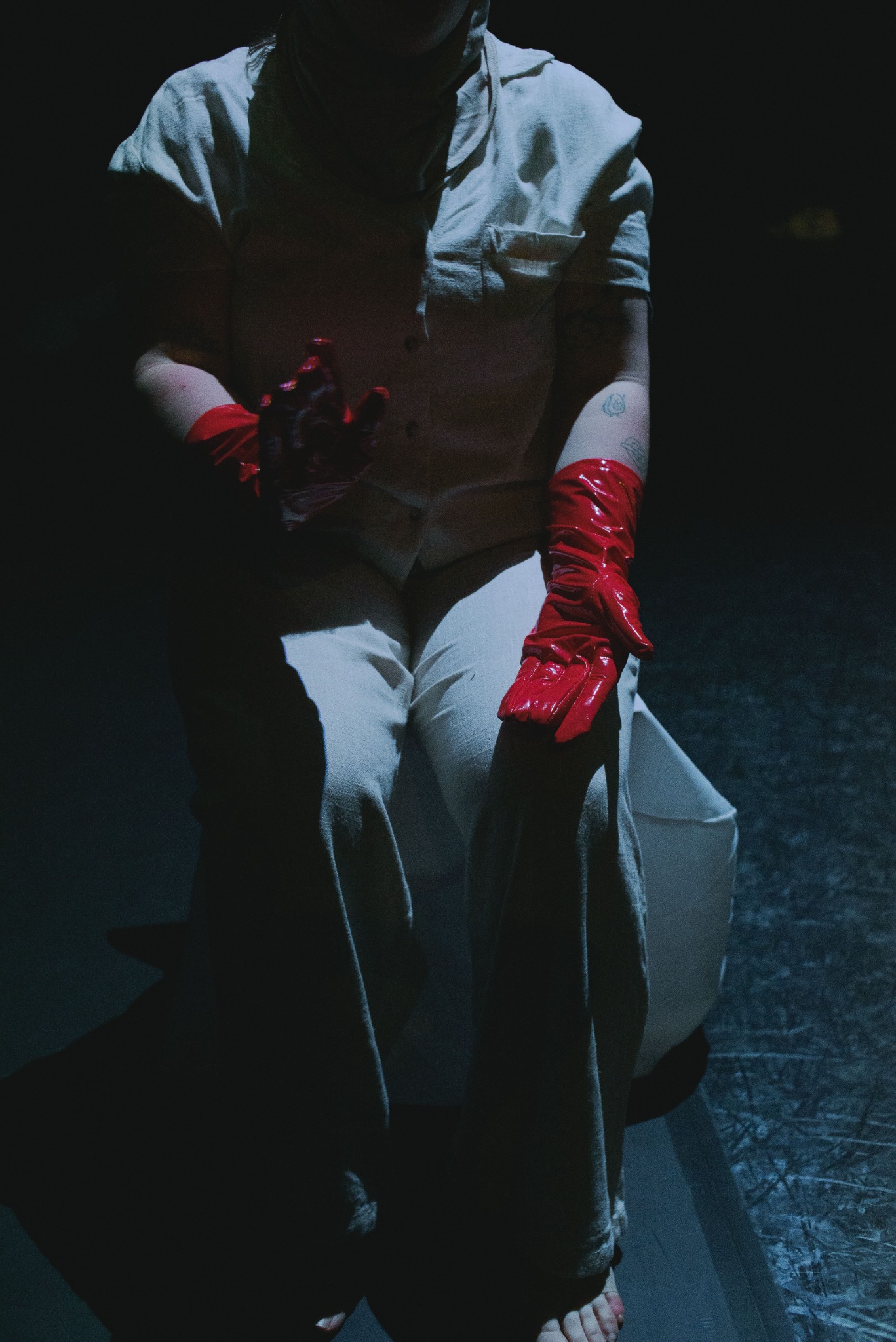 Interprète assise en costume clair et gants rouges sur scène
